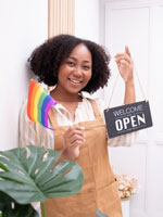 woman holding a pride flag and open sign